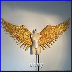 Large performance props show golden feather angel wings